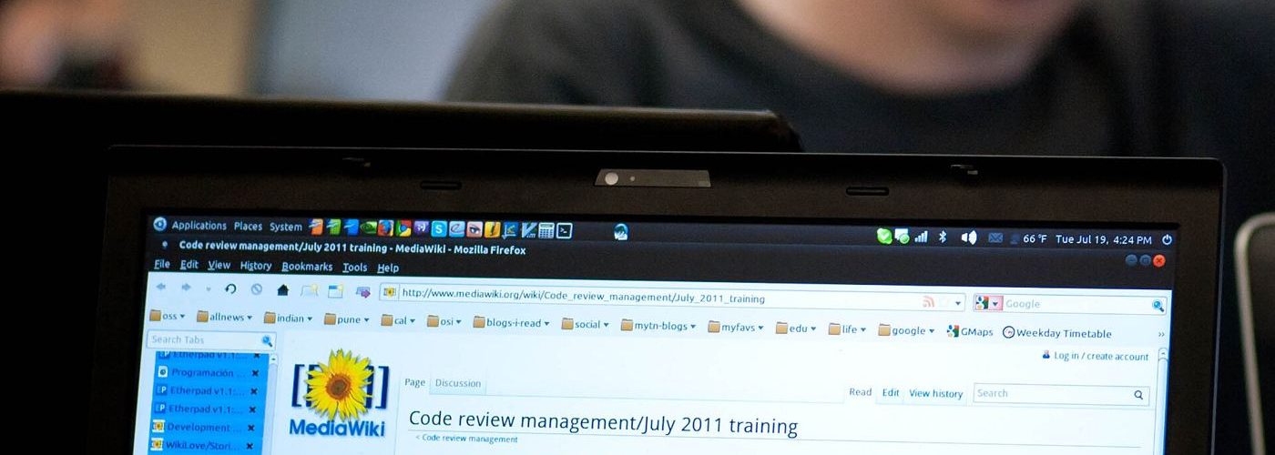 A programmer reviewing lines of code on a large monitor in a dim office.
