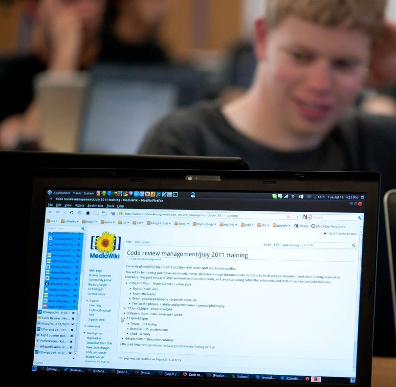 A programmer reviewing lines of code on a large monitor in a dim office.