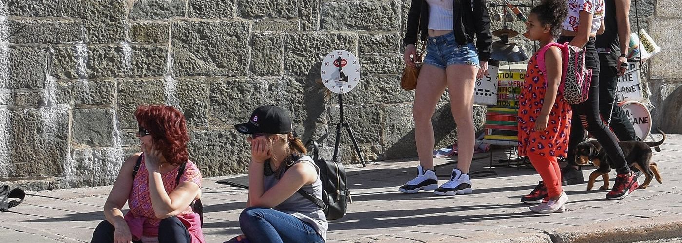 people resting in shade during hot city weather