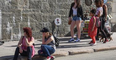 people resting in shade during hot city weather