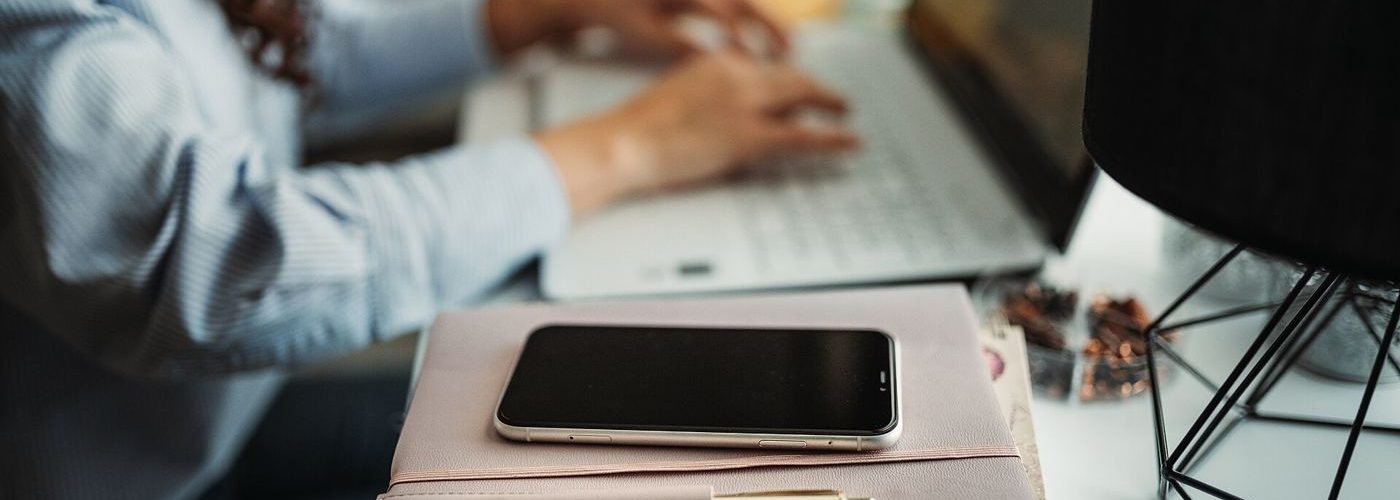 person working at desk with phone aside