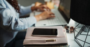 person working at desk with phone aside